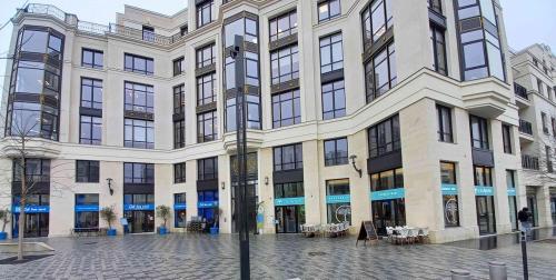 un grand bâtiment blanc avec des fenêtres donnant sur une rue dans l'établissement Charmant Appartement Disneyland, à Chessy