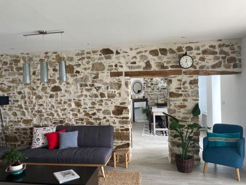 a living room with a couch and a stone wall at Demeure avec piscine in Saint-Viaud