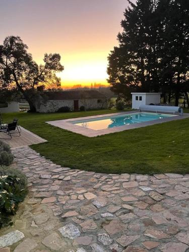 a backyard with a swimming pool and a stone walkway at Demeure avec piscine in Saint-Viaud