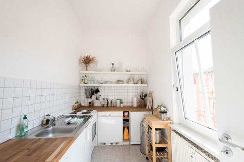 eine weiße Küche mit einem Waschbecken und einem Fenster in der Unterkunft Wohnung Peter in Weimar