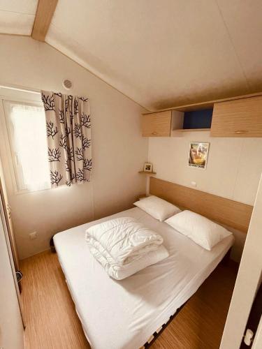 une petite chambre avec un lit blanc et une fenêtre dans l'établissement Mobil-home 3ch le Per Malou Camping Les Clarines, à La Bourboule