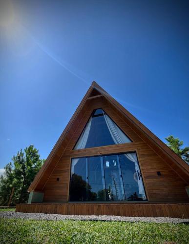 a house with a triangular roof with a large window at Cabana Arroio do sal in Arroio do Sal