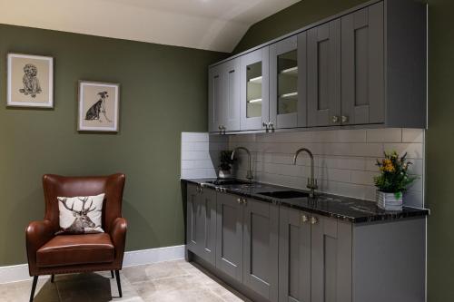 a kitchen with gray cabinets and a chair and a sink at Rock Mill 1 Bed Apartment 32 in Stoney Middleton