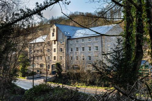a large stone building with a black roof at Rock Mill 1 Bed Apartment 32 in Stoney Middleton