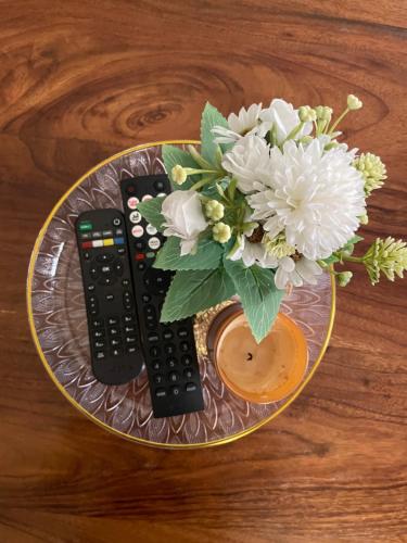 a glass plate with a vase of flowers and two remote controls at A-grade living-WiFi & parking in Kampala