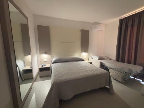 a hotel room with two beds and a mirror at Hotel La Mela in Varcaturo