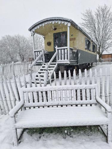 a snow covered bench next to a fence with a train at Roulotte les Mésanges in Rebecq-Rognon