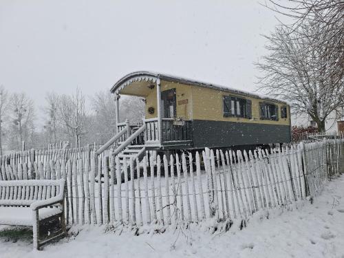 a train car behind a fence in the snow at Roulotte les Mésanges in Rebecq-Rognon