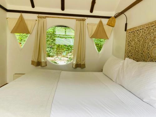 a bedroom with a white bed and two windows at Hotel Altiplanico Cajón del Maipo in San José de Maipo