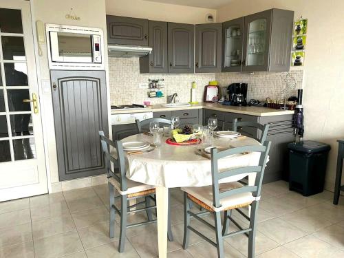 une cuisine avec une table et des chaises dans une cuisine dans l'établissement Appartement cosy vue mer à Merlimont, à Merlimont