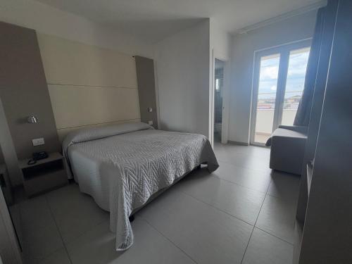 a bedroom with a bed and a large window at Hotel La Mela in Varcaturo