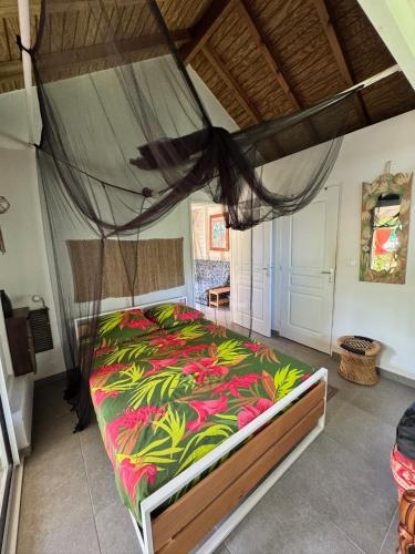 une chambre avec un grand lit avec une couverture colorée dans l'établissement L Anoli - Charmante Case Créole tout confort, à Baie-Mahault