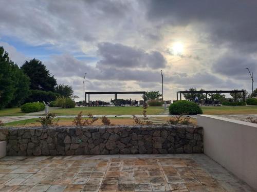 a stone wall in front of a park with the sun at Apart Altos del Virrey in Colonia del Sacramento