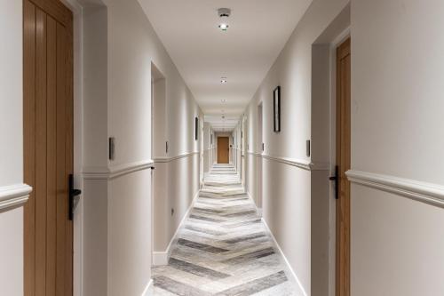 a hallway with white walls and a long hallway with wooden doors at Rock Mill 1 Bed Apartment 37 in Stoney Middleton