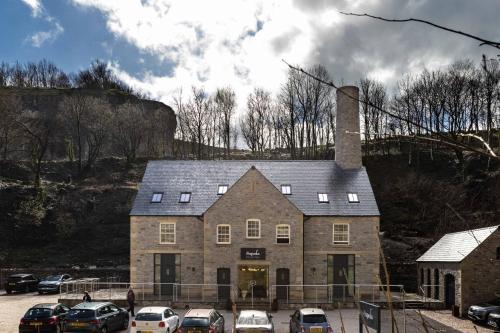 a large brick house with a chimney and parked cars at Rock Mill 1 Bed Apartment 37 in Stoney Middleton