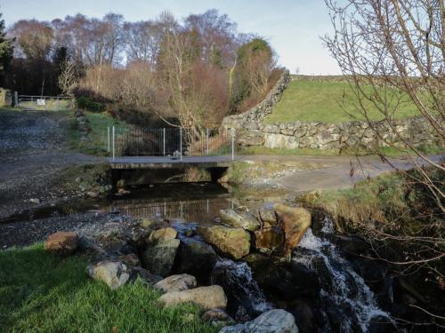 a bridge over a river with rocks in a field at Dan White's Cottage in Newry