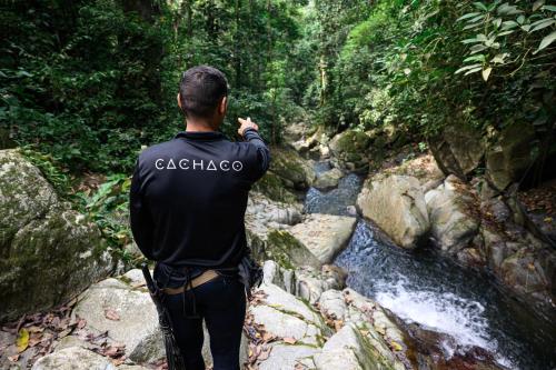 a man standing on some rocks near a stream at Tayrona Cachaco River Ecohostal in El Zaino