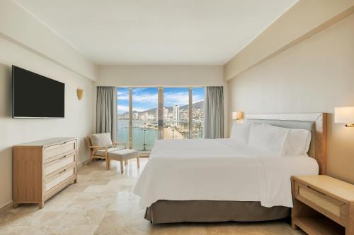 a bedroom with a large bed and a large window at Fiesta Americana Acapulco Villas in Acapulco