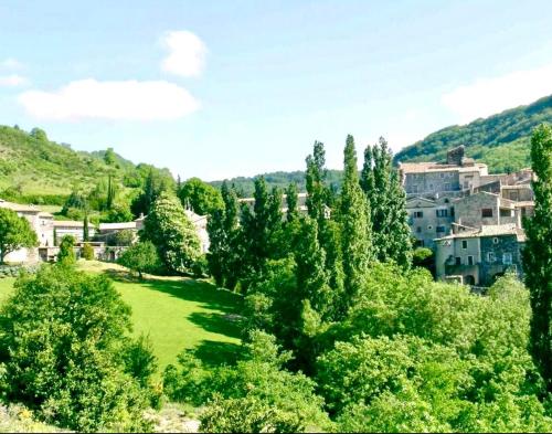 a green field with trees and buildings in the background at Gîte lePigeonnier - Ardèche in Aubignas