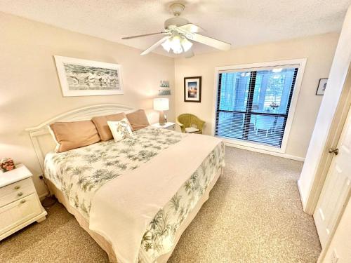a bedroom with a bed with a ceiling fan and a window at 750 Sandpiper in Destin