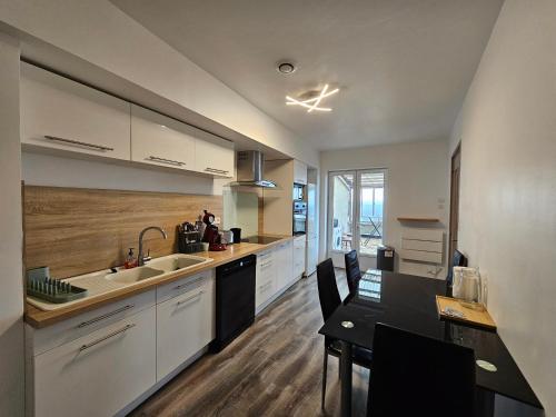 une cuisine avec des armoires blanches et une table et une salle à manger dans l'établissement La Coutellerie - vue panoramique - quartier médiéval, à Thiers