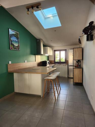 une cuisine avec des murs verts et un îlot de cuisine avec des tabourets dans l'établissement Charmante maison de village, à Bouillargues
