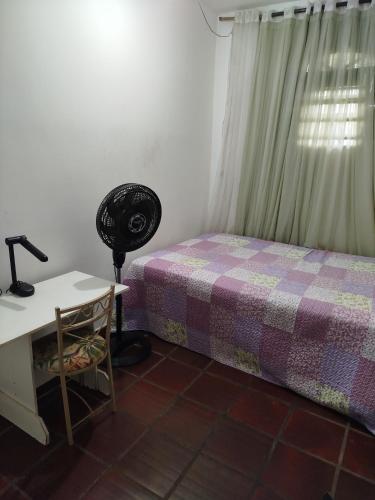 a bedroom with a bed and a desk with a lamp at Lar da Elis in Riacho Fundo