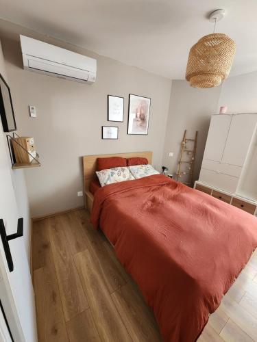 une chambre avec un grand lit avec une couverture rouge dans l'établissement Charmante maison de village, à Bouillargues