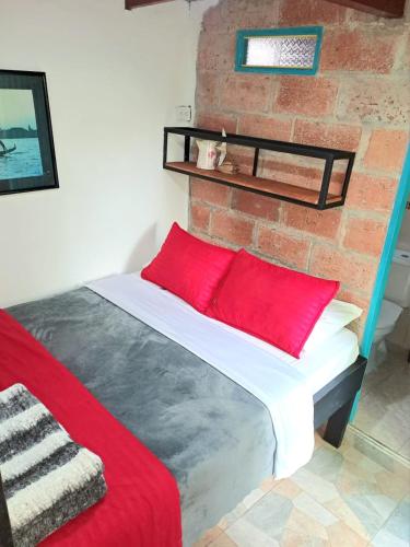 a bed with red pillows and a brick wall at Hotel Marrokos Aeropuerto José María Córdova in Rionegro