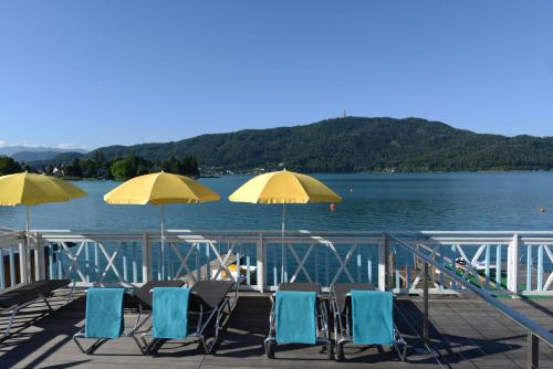 a group of chairs and umbrellas on a dock at Die WUNDER s Ferienpension in Pörtschach am Wörthersee