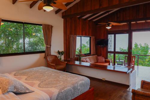 a bedroom with a bed and a desk and windows at Santa Juana Lodge & Nature Reserve in Quepos