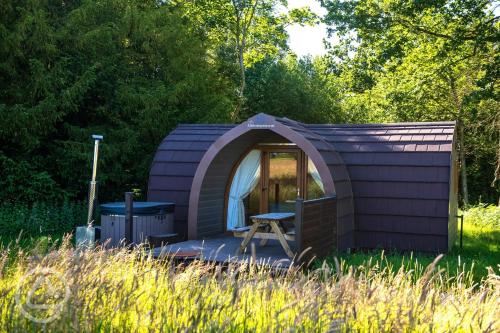 a purple shed with a picnic table in the grass at Missin' Link Glamping in West Hoathley