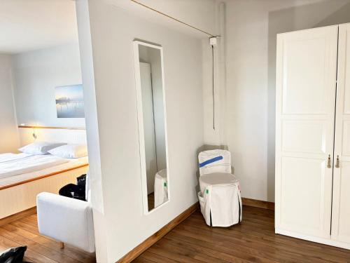 Cette chambre blanche comprend un lit et un miroir. dans l'établissement Pier 8 im Pierspeicher, à Kappeln