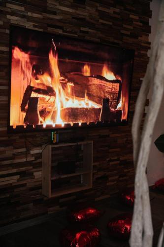 a brick fireplace with a fire in it at Capsule Thailande I Sauna I Balnéo I Console I jeux en bois I Cinéma I cour intérieure in Trith-Saint-Léger