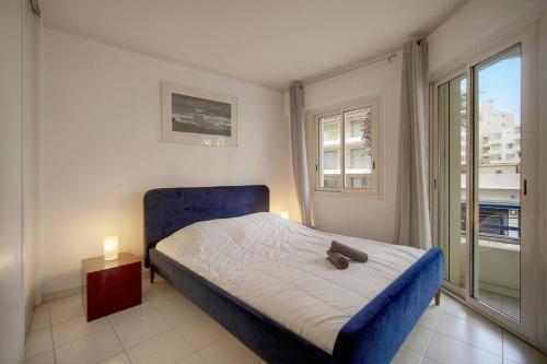 - une chambre avec un lit doté d'une tête de lit bleue et d'une fenêtre dans l'établissement FRGK - Le Dauphin - Juan les pins, à Antibes