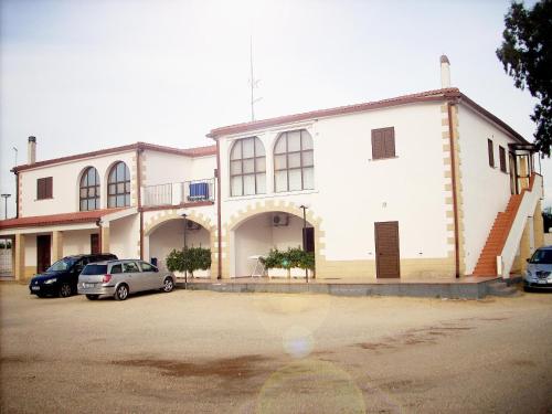 a white building with cars parked in a parking lot at Agriturismoteo in Bernalda