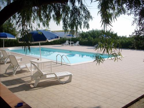 a swimming pool with chairs and umbrellas and a table and chairs at Agriturismoteo in Bernalda