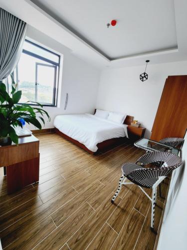 a bedroom with a bed and a table and chairs at Happy Bun Hotel Da Lat in Da Lat