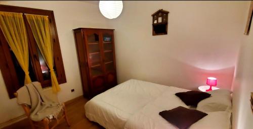 a bedroom with a white bed and a pink lamp at Le logis de l'Ajolaise in Vielle-Aure