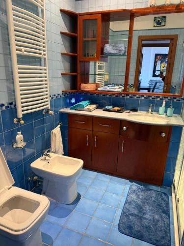 a blue tiled bathroom with a toilet and a sink at Marebleuhouse in Naples