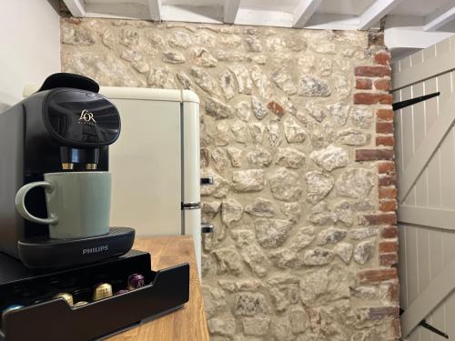 a coffee maker on a counter next to a stone wall at Albie Cottage in Grimston