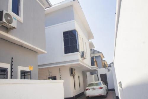 a white house with a car parked in a driveway at Two Bedroom Apartment Magodo Lagos in Magodo