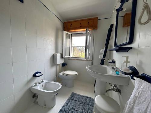 un bagno con due lavandini, un water e una finestra di Villa Malsine a Marzamemi