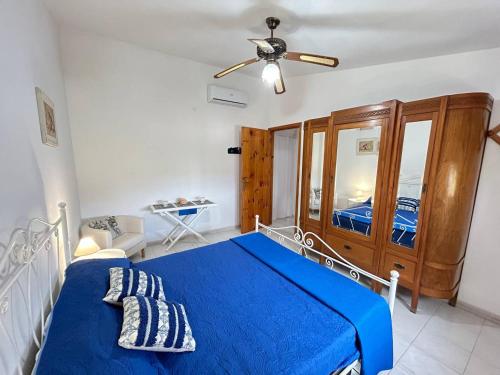 una camera con letto blu e ventilatore a soffitto di Villa Malsine a Marzamemi