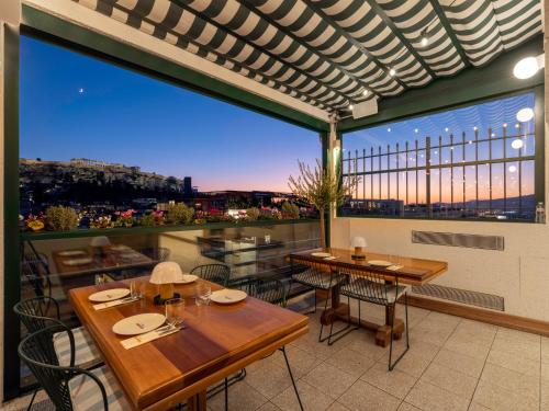 a patio with tables and chairs and a large window at Regal Hotel Mitropoleos in Athens