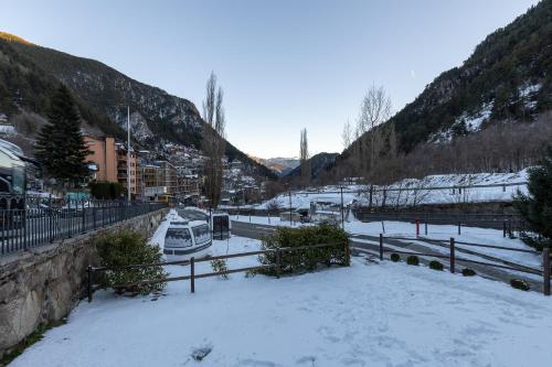 a snow covered street with cars parked on the road at Apartaments Sant Moritz in Arinsal