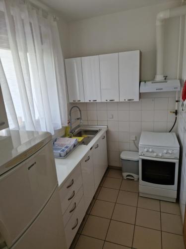 a small kitchen with white cabinets and a sink at Apartman CESTICA in Cestica