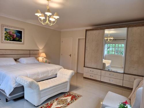 a bedroom with a large white bed and a mirror at A Casa Serena in Morro Reuter