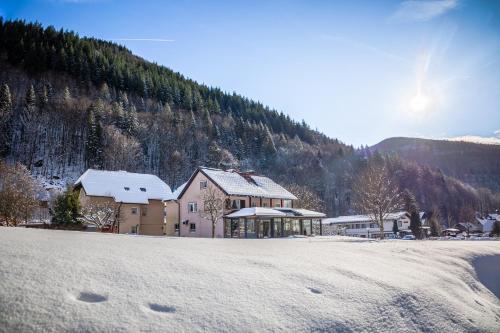 a house in the snow in front of a mountain at Landgasthaus Kurz Hotel & Restaurant am Feldberg - Schwarzwald in Todtnau