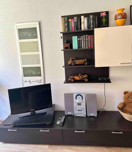a desk with a computer and a shelf with books at Geräumige 2-Zimmer Ferienwohnung in Freiburg in Freiburg im Breisgau